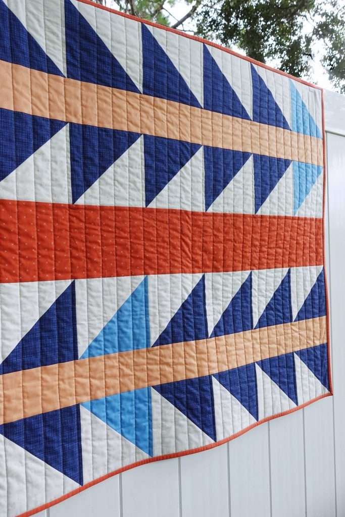 Modern orange and blue baby quilt using the free Explore Quilt Pattern by Homemade Emily Jane