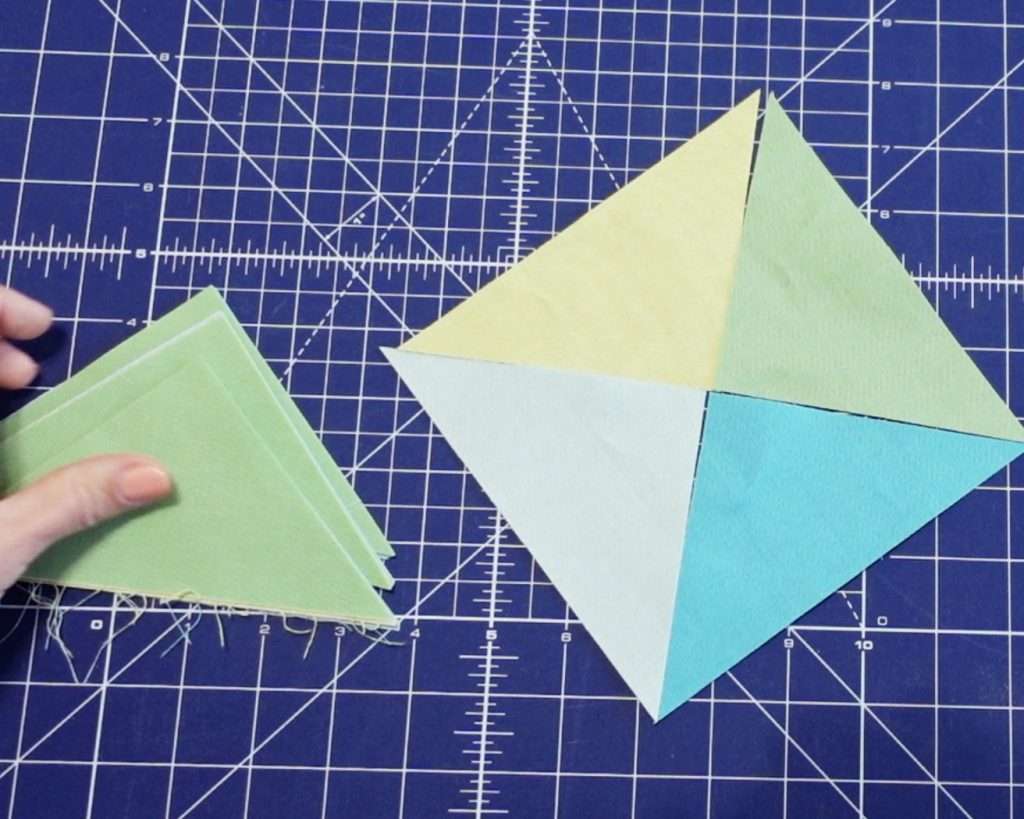 quarter square triangles make up a scrappy hourglass quilt block in this simple quilt block tutorial
